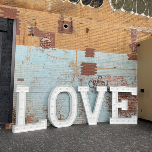 LOVE letter sign against graffitied brick wall